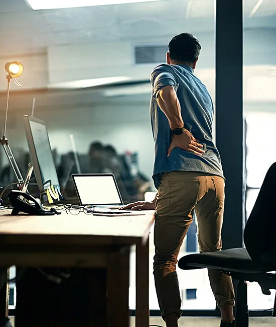 Employé souffrant du dos devant un poste de travail mal adapté